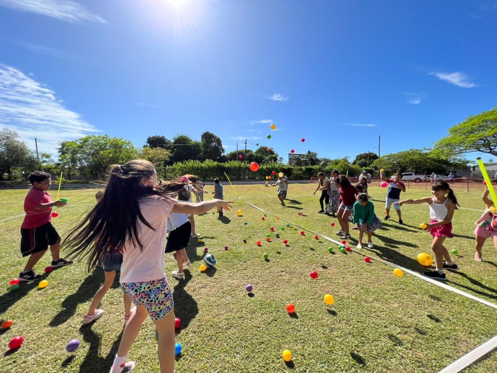niños enfrentados en dos equipos participan de un juego con pelotitas de colores